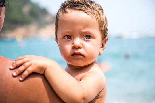 Over shoulder view of mother carrying male toddler son on beach, Begur, Catalonia, Spain