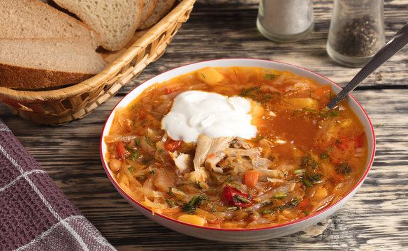 Ukrainian borsch in a white porcelain dish on an old wooden table