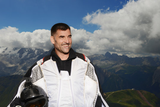 Portrait of base jumper wearing wingsuit looking away smiling, Dolomite mountains, Canazei, Trentino Alto Adige, Italy, Europe