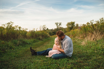 Daughter sitting on fathers lap on grass