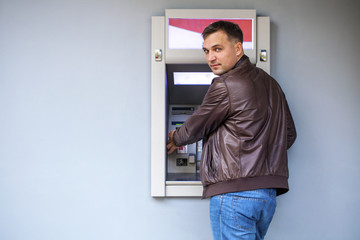 Young man inserting a credit card to ATM