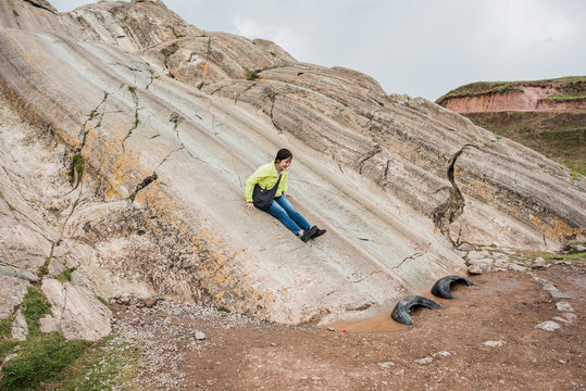 Woman sliding down rock slide, Sacsayhuaman, Cusco, Peru, South America