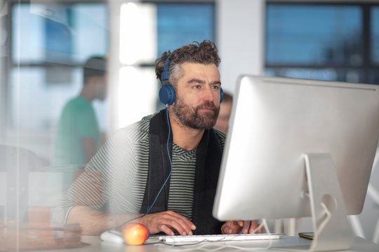 Man in office wearing headphones, using computer
