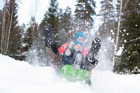 Man And Son On Speeding Toboggan In Snow Covered Forest