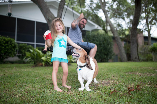 Father and daughter in garden with pet dog