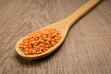 Turkish Red Lentil legume. Spoon and grains over wooden table.