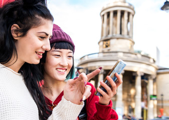 Two young stylish women looking at smartphone, London, UK
