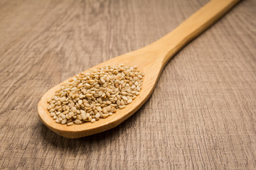 Sesame. Spoon and grains over wooden table.