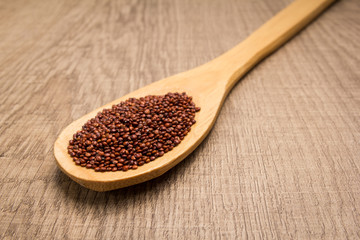 Red Quinoa seed.Spoon and grains over wooden table.
