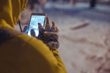 young woman standing at night winter city park in the evening and taking picture