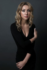 portrait of beautiful woman in black dress standing on dark background