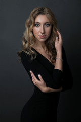 portrait of beautiful woman in black dress standing on dark background