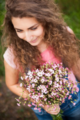 Fototapeta premium Beautiful curly woman with pink flowers looking down and smile