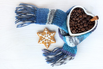 favorite winter break/ Ginger cookies and mug in the form of heart filled with roasted coffee and cinnamon grains and wrapped in scarf top view 