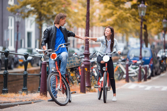 Young happy caucasian couple on bikes in old streets in Amsterdam