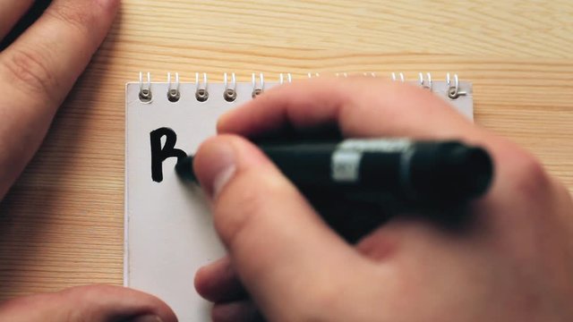 Budget planing concept. Top view of notepad, man writing word Budget, wooden background. Write idea success solution concept
