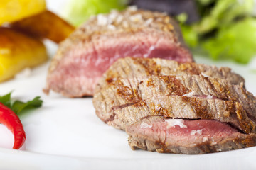Scheiben eines Steaks auf Holz mit Rosmarin