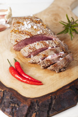 Scheiben eines Steaks auf Holz mit Rosmarin