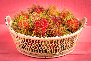 rambutan fruit on wood color pink. in basket