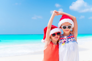 Obraz premium Adorable little kids in Santa hat during Christmas beach vacation. New Year on the beach