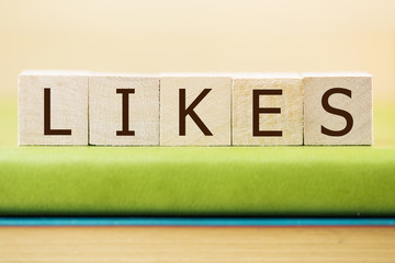 Likes written in wooden cubes on a green book