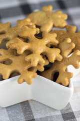 Traditional tasty Czech gingerbreads, Christmas snowflakes in white star shaped bowl on grey chequered tablecloth