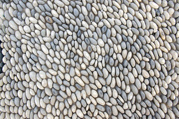 Detail of a walkway made of river pebbles, stone background, light grey and white colors