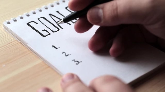 Goals concept. Notebook with goals list on wooden table. Motivation strategy write idea success solution concept.