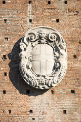 Stone coat of arms exposed on a bricks wall in the Castello Sforzesco in Milan.