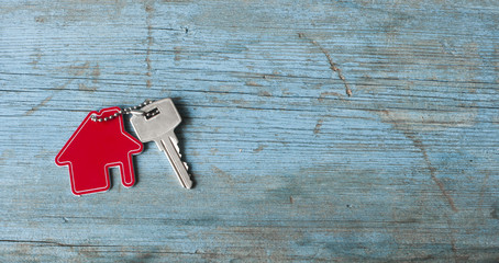 Key with house icon on wooden background
