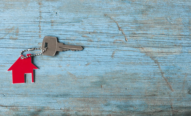Key with house icon on wooden background