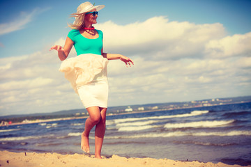 Blonde woman wearing dress walking on beach