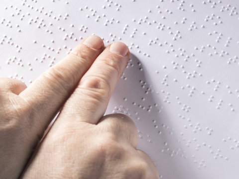 Cropped image of child using braille to read book at school