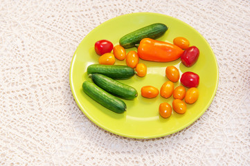 Green plate with mix of colorful vegetables on creamy handmade tablecloth