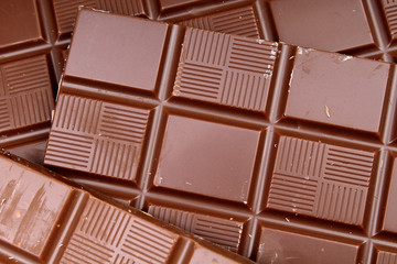 Chocolate bars as background. Milk and dark shiny chocolate texture. Stack chocolates pattern. Stunning beautiful cacao brown choco dessert sweets.