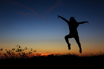 Silhouette of a woman jumping happily