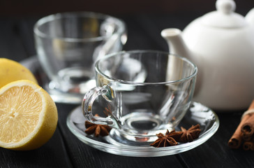Tea time. Empty glass teacups with lemon and spices on black background