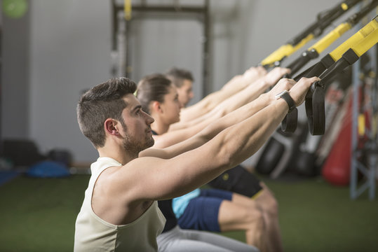 People training suspension rope in gym. Side view