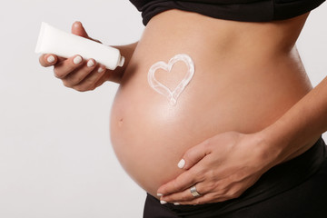
Pregnant woman applying moisturizer on belly, preventing pregnancy stretch marks - obrazy, fototapety, plakaty