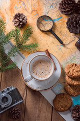 cup of cappuccino on a wooden table, map and magnifier.