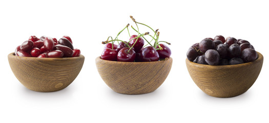 Dark red berries on a white background. Cornels, cherries and grapes in a wooden bowl. Berry with copy space for text. Ripe and tasty black berry isolated on white.