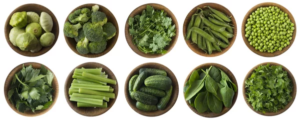 Wall murals Fresh vegetables Green vegetables and herbs isolated on a white background. Squash, brocoli, green peas, cucumbers and leaves parsley, celery, cilantro, spinach in wooden bowl with copy space for text. Top view.