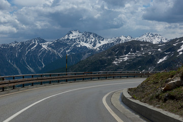 Fototapeta premium Dangerous panoramic serpentine road high in the Alps between melting snow