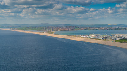 View from the South West Coast Path  towards Fortuneswell and Chesil Beach, Isle of Portland, Jurassic Coast, Dorset, UK - with clouds over Weymouth in the background