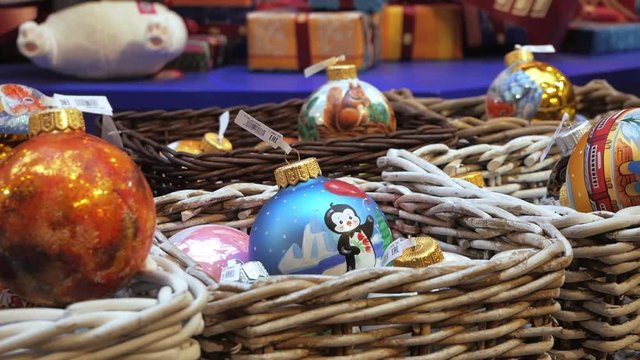 Variety of bright colorful Christmas baubles put in baskets on sale in shopping center. Panning, close up