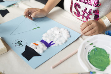 Obraz na płótnie Canvas Hands of a 10 year old girl doing a Christmas craft. Horizontal shot