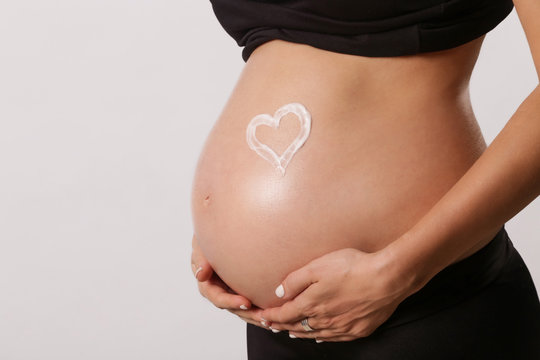 
Pregnant woman applying moisturizer on belly, preventing pregnancy stretch marks