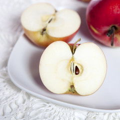 the Red apples and halves of apples on a plate on a lace napkin