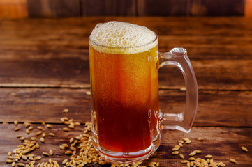 Indoor view of glass of beer with wheat in the base on a wooden table on a dark pub
