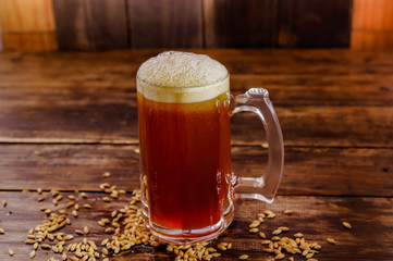 Indoor view of glass of beer with wheat in the base on a wooden table on a blurred background